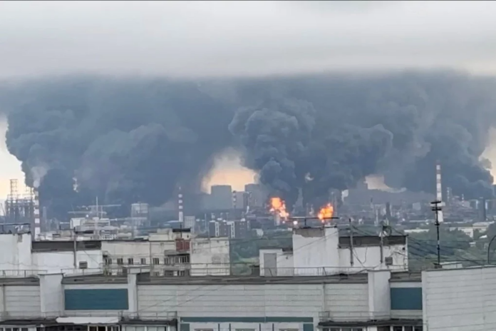 d6d71a3a-be15-4e86-97ae-6328f5810846_6ffc38a6 Thick, towering plumes of industrial black smoke rising rapidly over city apartment blocks from a compromised energy complex.